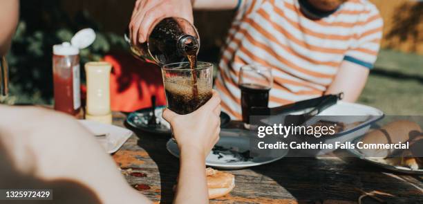 child holds out a glass as a man pours a carbonated beverage into it - cola stockfoto's en -beelden