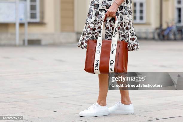 Cognac and cream colored tote bag by Chloe and white sneaker by Axel Arigato as a detail of fashion designer Eva Lutz during a street style shooting...