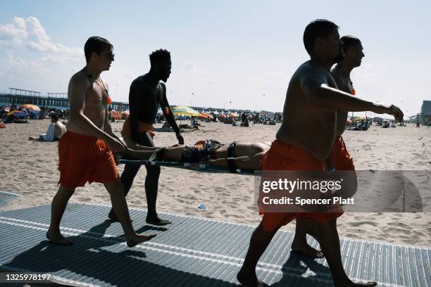 Lifeguards practice a rescue as people cool off at Coney Island in Brooklyn on one of the first hot days of the year on June 28, 2021 in New York...