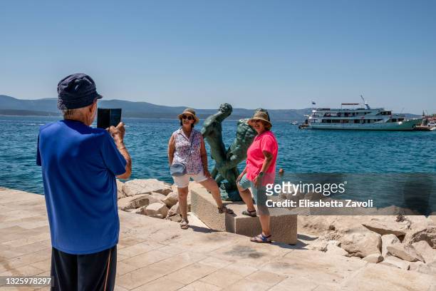 Some Israeli tourists take pictures on the main pier on June 28, 2021 in Bol, Croatia. They are part of a bigger group from Israel who rent a charter...