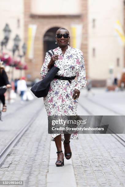 Auma Obama wearing a cream colored midi length longsleeve dress with all over multicolor floral print and ruffle details by Isabel Marant Etoile, a...