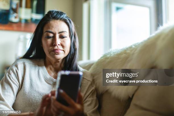 femmina adulta matura di etnia ispanica usando lo smartphone nella serie di foto di casa - introspection foto e immagini stock