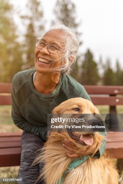 active ethnic senior woman enjoying the outdoors with her pet dog - ouderen stockfoto's en -beelden