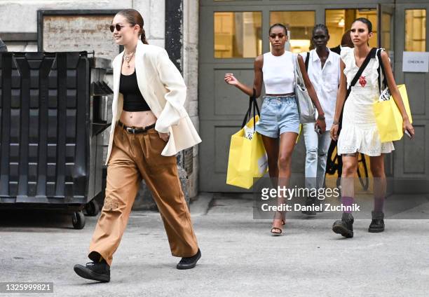 Gigi Hadid is seen wearing a white blazer, black crop top, brown pants and black Converse sneakers outside the Marc Jacobs show on June 28, 2021 in...