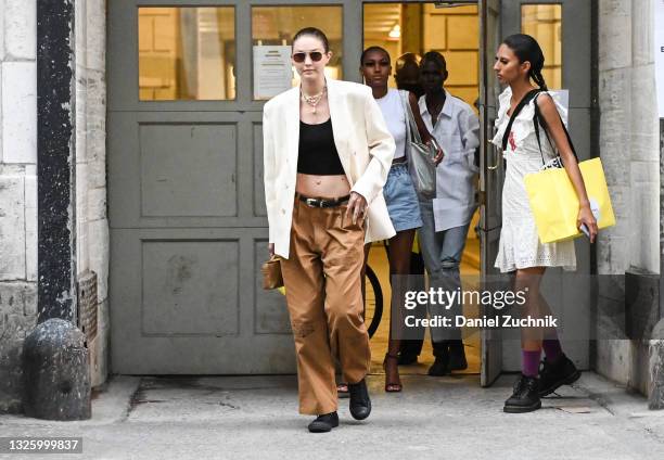 Gigi Hadid is seen wearing a white blazer, black crop top, brown pants and black Converse sneakers outside the Marc Jacobs show on June 28, 2021 in...