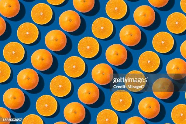 arranged oranges cut in half repetition on blue - orange stock pictures, royalty-free photos & images