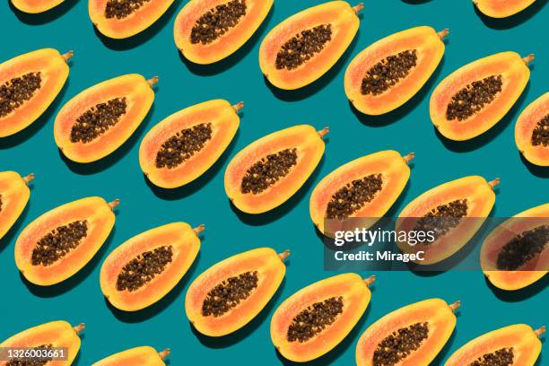 arranged papaya cut in half repetition on turquoise - papaya stock pictures, royalty-free photos & images