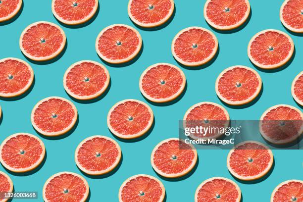 arranged pink grapefruit slices repetition on turquoise - pink grapefruit stock pictures, royalty-free photos & images