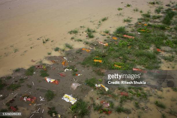 Bodies, many of which are believed to be COVID-19 victims, are seen partially exposed in shallow sand graves as rainwater inundated the site and...