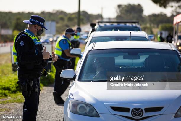 Member of the police force inspects cars at a Border Check Point on Indian Ocean Drive, north of Perth on June 29, 2021 in Perth, Australia. Lockdown...