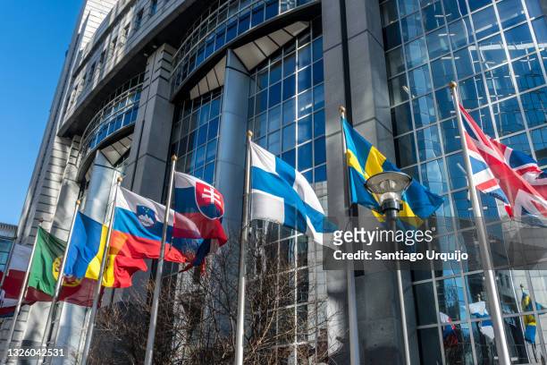 european national flags in front of european parliament building - european parliament stock pictures, royalty-free photos & images