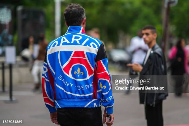 Guest wears a blue red and white logo of the football team 'Paris Saint Germain zipper sweater, black denim jeans pants, silver rings, during Paris...