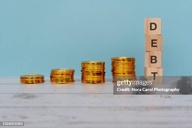 debt text on wood block with stack of gold coins - carol grow stock-fotos und bilder