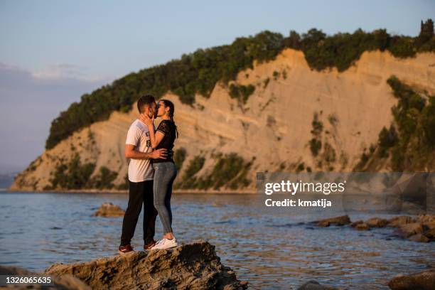 young couple kissing on coastline - styles stock pictures, royalty-free photos & images