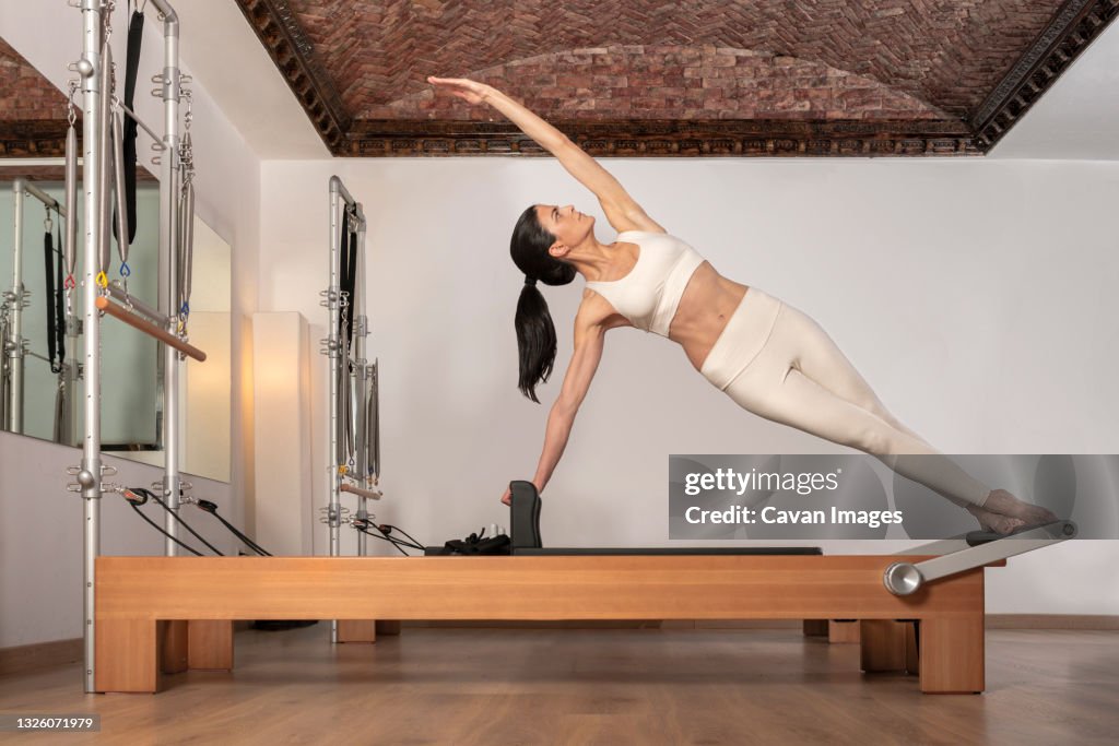 Brunette girl doing pilates exercise for the oblique abdominals