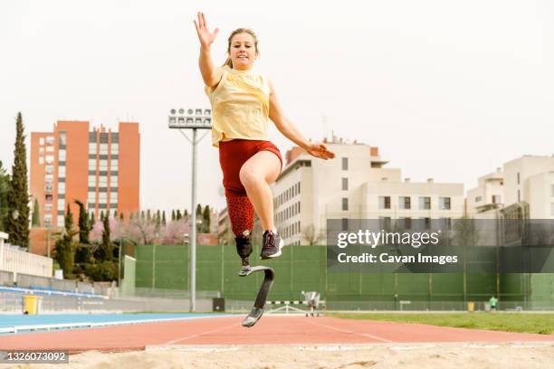 female athlete with disability running towards sandpit - adaptive athlete - fotografias e filmes do acervo