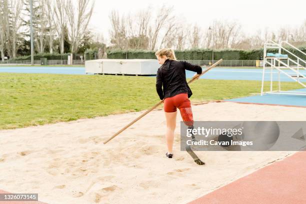 Handicapped sportswoman preparing sand on stadium