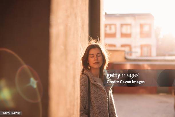 portrait of young woman with eyes closed standing in city - autumn sadness stock pictures, royalty-free photos & images