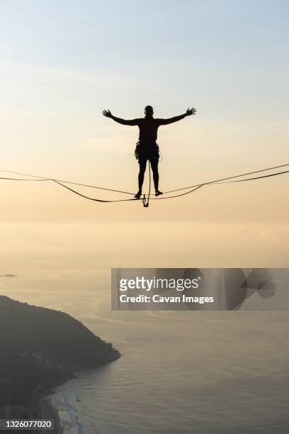 beautiful view to male highliner silhouette on mountain sunrise - highlining stock pictures, royalty-free photos & images