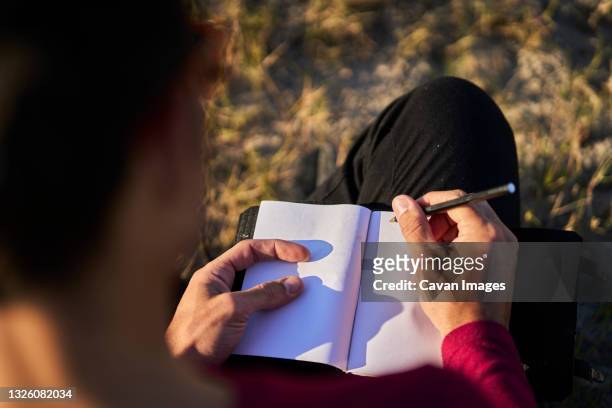 young man writing on the beach - poet stock pictures, royalty-free photos & images