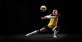 Female professional volleyball player with ball isolated on black studio background. The athlete, exercise, action, sport, healthy lifestyle, training, fitness concept.