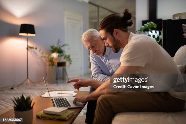 grandson teaching grandfather to use laptop - baby boomer millennial stock pictures, royalty-free photos & images