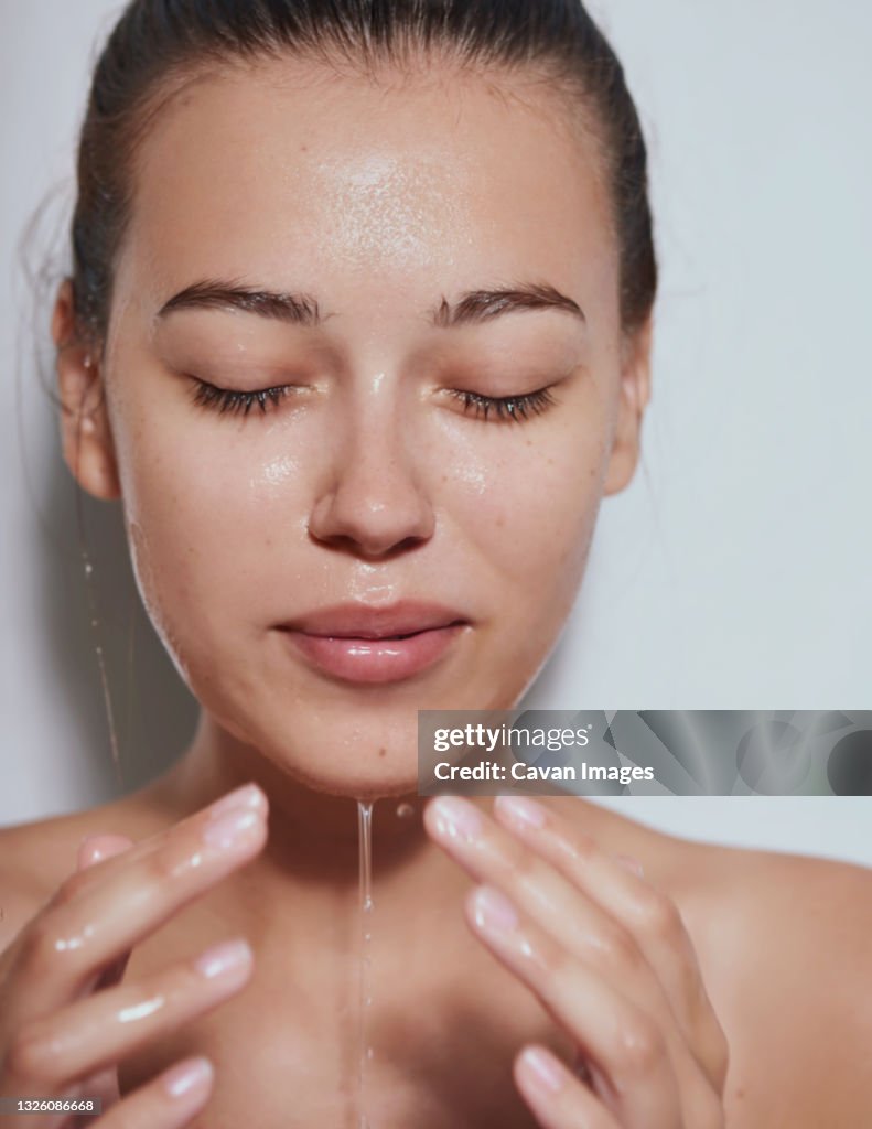 Young beautiful woman with clean fresh skin with splash of water - white background
