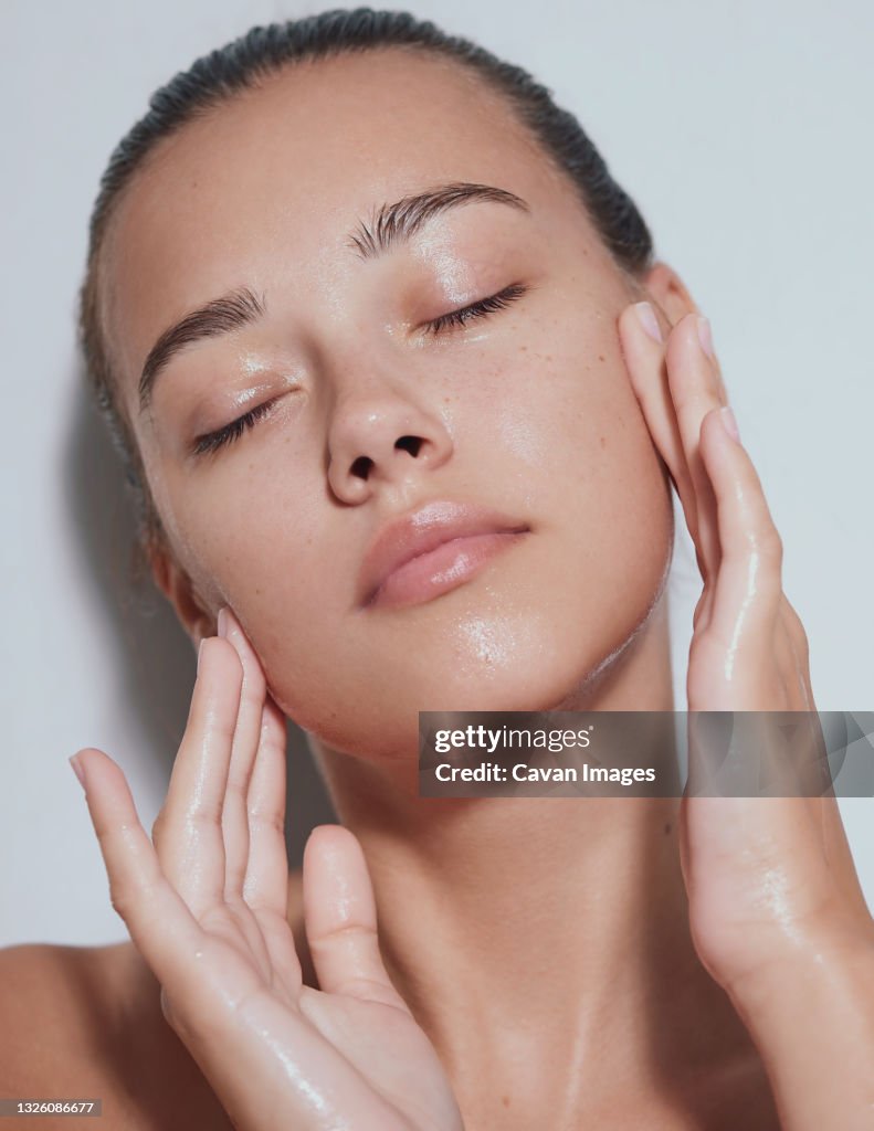 Young beautiful woman with clean fresh skin with splash of water - white background