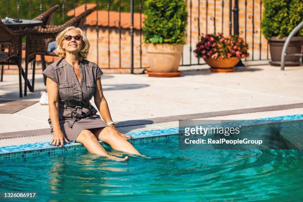 senior woman splashing pool water with her leg - dip toe stock pictures, royalty-free photos & images