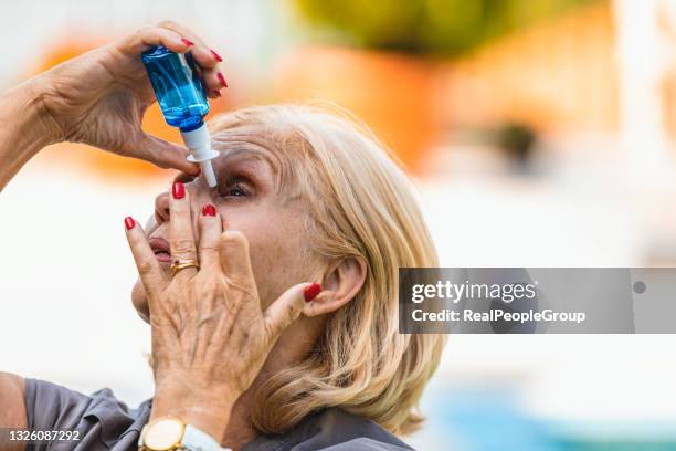 taking care of her eyes. senior woman putting eye drops - dry eye stock pictures, royalty-free photos & images