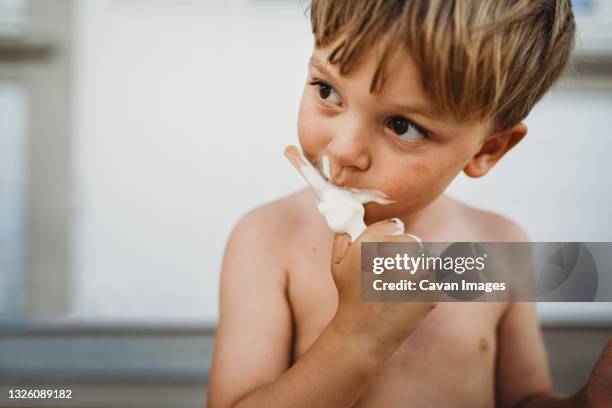 cute young boy eating ice cream looking to the side outside in summer - lollies stock pictures, royalty-free photos & images