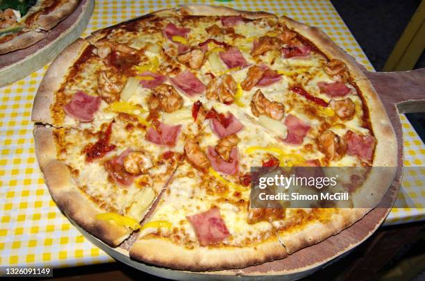 large hawaiian pizza with shrimp and yellow capsicum on a serving board - hawaiian pizza stock pictures, royalty-free photos & images