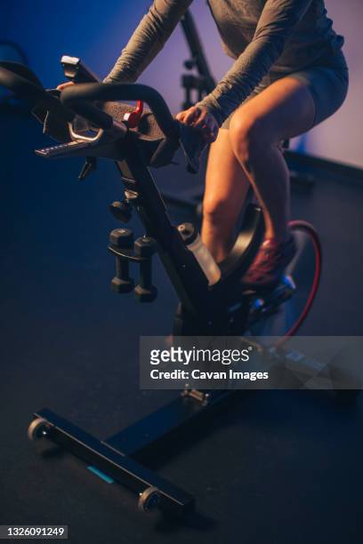 a high angle of a caucasian woman pedaling on a stationary bike. - peloton tread stock pictures, royalty-free photos & images