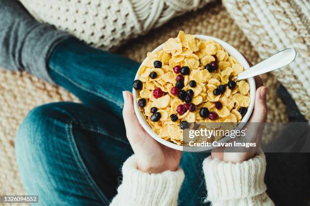 young woman holding a bowl of healthy breakfast cereals at home. - corn flakes imagens e fotografias de stock