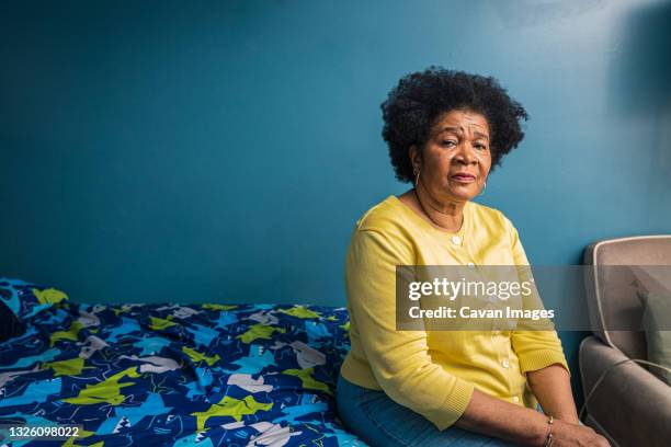 portrait of serious senior woman sitting in bedroom at home - 70s afro stock-fotos und bilder