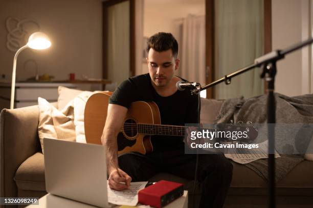 male guitarist writing song at home - songwriter stock pictures, royalty-free photos & images
