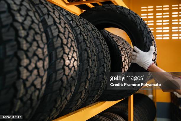 hand of a tire changer lifting a car tires out of a warehouse. - car wheel bildbanksfoton och bilder