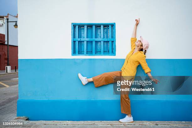 cheerful woman dancing by wall - standing on one leg fotografías e imágenes de stock