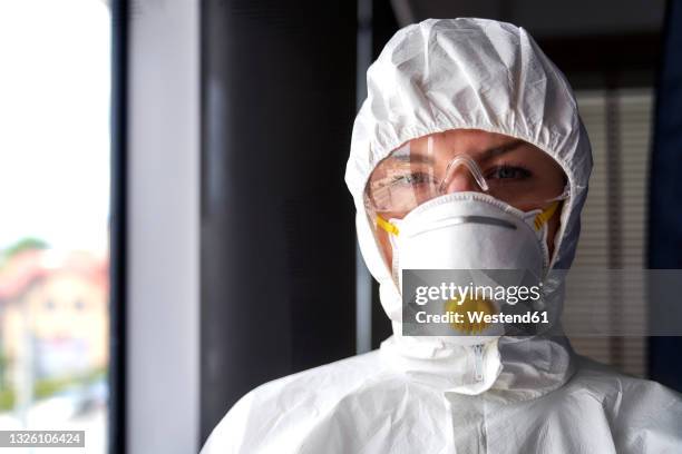 female frontline worker wearing protective face mask at office - schutzanzug stock-fotos und bilder