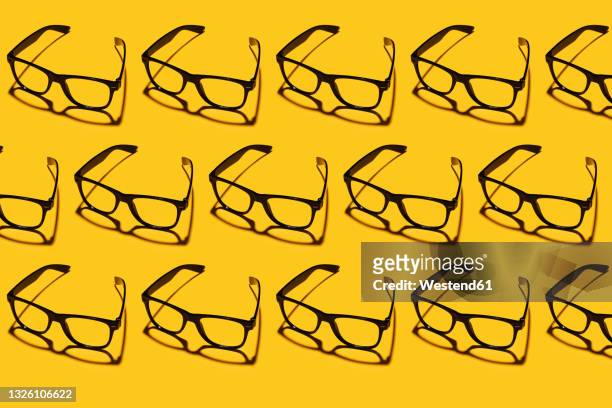 pattern of rows of simple classic eyeglasses flat laid against yellow background - reading glasses 個照片及圖片檔
