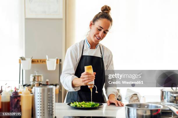 female chef pouring sauce on vegetable while preparing food in restaurant - pouring sauce stock pictures, royalty-free photos & images