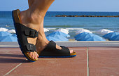 Black and blue men's sandals walking on the beach in summer vacation time
