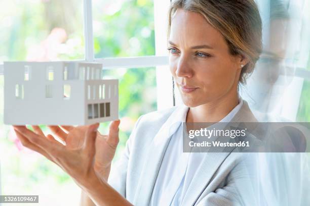 businesswoman with architectural model by window - architekt mit plan frontal stock-fotos und bilder