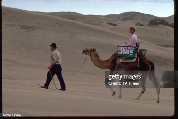 Actress Alexandra Bastedo riding a camle through the desert, circa 1969.