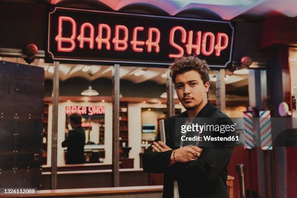 male hairdresser with scissor and comb standing outside barber shop - barber stock pictures, royalty-free photos & images
