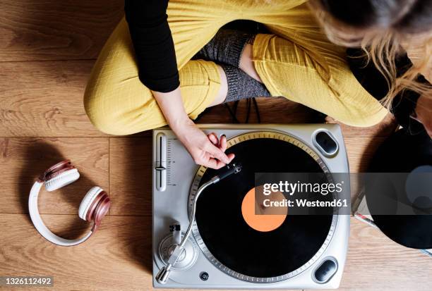 woman adjusting tonearm of turntable while sitting on floor at home - vinyl records stock pictures, royalty-free photos & images