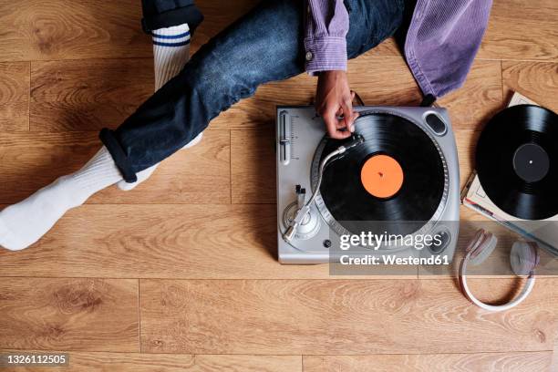 young man playing record disk on turntable at home - deck stock pictures, royalty-free photos & images