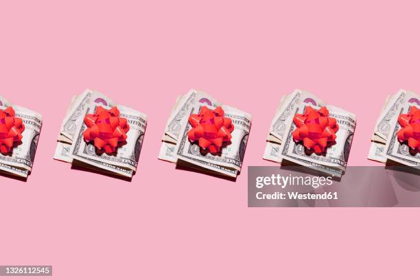 studio shot of row of folded dollar bills with red gift bows - lint strik stockfoto's en -beelden