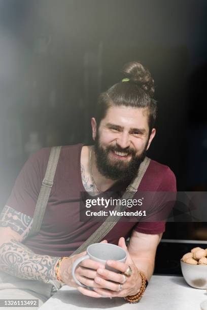 smiling man holding coffee cup while sitting at home - coque masculino - fotografias e filmes do acervo