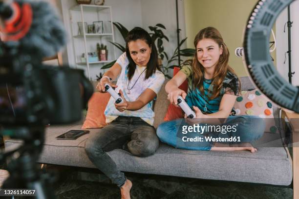 concentrated female gamers playing video game while vlogging at home - girl camera bildbanksfoton och bilder